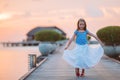 Silhouette of adorable little girl on wooden jetty at sunset