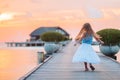 Silhouette of adorable little girl on wooden jetty at sunset