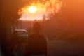 Silhouette of adult woman walking alone along city street during beautiful warm sunset Royalty Free Stock Photo