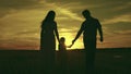 silhouette affectionate parents with child sunset. happy african family sunset park. mother father hold kid hands Royalty Free Stock Photo