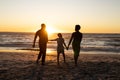 Silhouette african american boy holding mother and father\'s hands and standing on beach at sunset Royalty Free Stock Photo