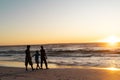 Silhouette african american boy with mother and father walking on beach against sky at sunset Royalty Free Stock Photo