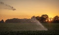 Silhouette of agricultural irrigation system watering cornfield at sunset. Cornfield irrigation using the center pivot sprinkler Royalty Free Stock Photo