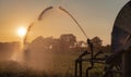 Silhouette of agricultural irrigation system watering cornfield at sunset. Cornfield irrigation using the center pivot sprinkler Royalty Free Stock Photo