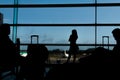 Silhouette of airline passengers in an airport lounge at the wide observation window watching an airplane flying of Royalty Free Stock Photo