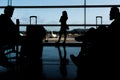 Silhouette of airline passengers in an airport lounge at the wide observation window watching an airplane flying of Royalty Free Stock Photo