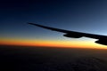 Silhouette of Airplan wing in twilight sky, with beautiful light from dramatic sunset, Romantic view from airplane window.