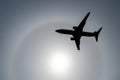 Silhouette of an airplane in the sky sun and halo in the clouds. Royalty Free Stock Photo