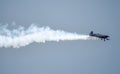 Silhouette of an airplane with trail of smoke behind against background of blue sky. Royalty Free Stock Photo