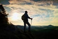 Silhouette of alone hiker with poles in hand. Tourist with sporty backpack stand on rocky view point above misty valley. Sunny spr Royalty Free Stock Photo