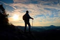 Silhouette of alone hiker with poles in hand. Tourist with sporty backpack stand on rocky view point above misty valley. Sunny spr Royalty Free Stock Photo