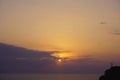 Silhouette alone lonely man are standing on hill against sunset purple orange sky with round sun over sea Royalty Free Stock Photo