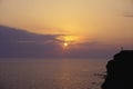 Silhouette alone lonely man are standing on hill against sunset purple orange sky with round sun over sea Royalty Free Stock Photo