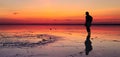 Silhouette of alone man looking toward vibrant sunset reflected in shallow waters of solt lake Royalty Free Stock Photo