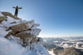 Silhouette of alone tourist standing on snowy mountain top in winner pose with raised hands enjoying view and achievement on Royalty Free Stock Photo