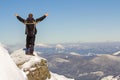 Silhouette of alone tourist standing on snowy mountain top in winner pose with raised hands enjoying view and achievement on Royalty Free Stock Photo