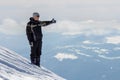 Silhouette of alone tourist standing on snowy mountain top in winner pose with raised hands enjoying view and achievement on Royalty Free Stock Photo