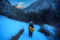 Silhouette of alone tourist standing on snowy mountain top in winner pose with raised hands enjoying view and achievement on Royalty Free Stock Photo