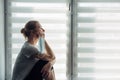 Silhouette of alone woman sitting on the windowsill on the background of window. Quarantine, self-isolation, stay at home. Concept