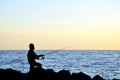 Silhouette of angler fishing on the rock at the beach of malacca straits