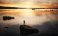 Silhouette of angler on sunset. Sun reflecting in water with stones and islands. Baltic sea, gulf of Finland