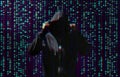 Silhouette of anonymous hacker and digital binary code on dark background. Cyber attack concept