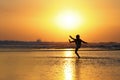 Silhouette of anonymous unknown young kid having fun playing on sea water at the beach kicking on wet sand with amazing beautiful