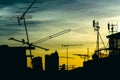 Silhouette antenna on building rooftop with sunrise in urban or city area, early morning time.