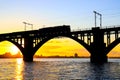 Silhouette of arched railway bridge and a train on the Dnieper river at beautiful sunset. Dnipo city, Dnepropetrovsk