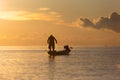 Silhouette of asian Fisherman on a traditional wooden boat during sunrise