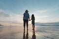 Silhouette of asian mother and daughter holding hand together standing on the beach looking at the beautiful sea and sky Royalty Free Stock Photo