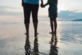 Silhouette of asian mother and daughter holding hand together standing on the beach looking at the beautiful sea and sky Royalty Free Stock Photo