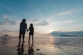 Silhouette of asian mother and daughter holding hand together standing on the beach looking at the beautiful sea and sky Royalty Free Stock Photo