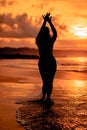 the silhouette of an Asian teenager with a tall body is dancing ballet on the waves on the beach