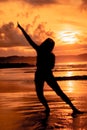 the silhouette of an Asian teenager with a tall body is dancing ballet on the waves on the beach