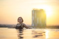 Silhouette of asian woman relaxing in infinity swimming pool with sunset view with high rise skyscape urban downtown, Happiness Royalty Free Stock Photo
