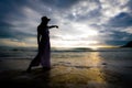 Silhouette of asian woman wearing stylish hat and clothes pointing at the sky and looking to the ocean Royalty Free Stock Photo