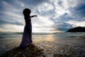 Silhouette of asian woman wearing stylish hat and clothes pointing at the sky and looking to the ocean Royalty Free Stock Photo