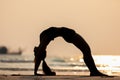 Silhouette of Asian young woman practice Yoga bridge Pose on the sand and beach Royalty Free Stock Photo