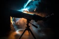 Silhouette of a astronomy telescope on dark foggy backlight