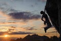 Silhouette of athletic woman climbing steep rock wall