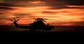 Silhouette of an attack helicopter at against a dramatic cloudy sky at sunset Royalty Free Stock Photo