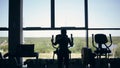 Silhouette of attractive young woman at the gym exercising on the xtrainer machine