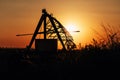 Silhouette of automated farming irrigation pivot sprinkler system in cultivated field in summer sunset