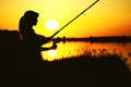 Silhouette of awoman with a fishing rod on the river bank Royalty Free Stock Photo