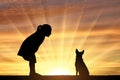 Silhouette of a baby girl and her dog looking at the sunset. Royalty Free Stock Photo