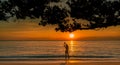 Silhouette back view of woman watching beautiful sunset at tropical paradise beach. Happy girl wear bikini and straw hat Royalty Free Stock Photo