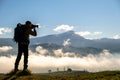 Silhouette of a backpacker photographer taking pictures of morning landscape in autumn mountains with digital camera Royalty Free Stock Photo