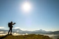 Silhouette of a backpacker photographer taking pictures of morning landscape in autumn mountains with digital camera Royalty Free Stock Photo