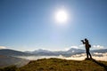 Silhouette of a backpacker photographer taking pictures of morning landscape in autumn mountains with digital camera Royalty Free Stock Photo